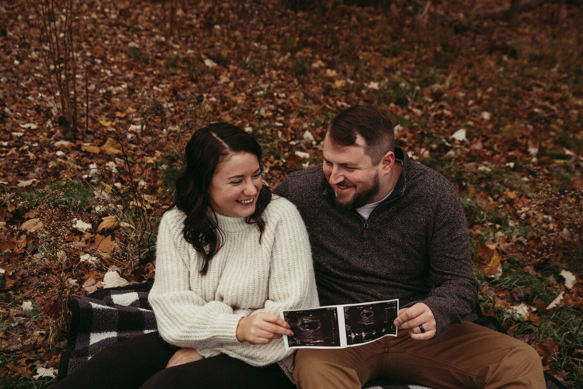 Couple announce their news of expecting first child in field of a cool fall day.