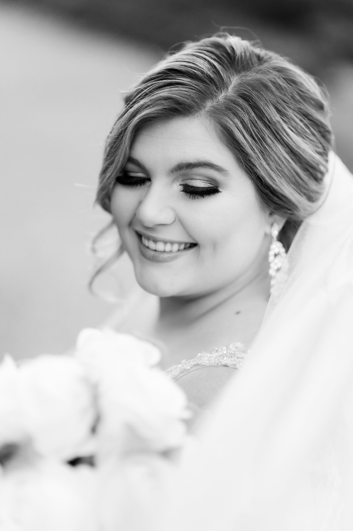 bridal portrait in black and white of bride wearing her veil and looking down at her bridal bouquet photographed by Little Rock wedding photographer
