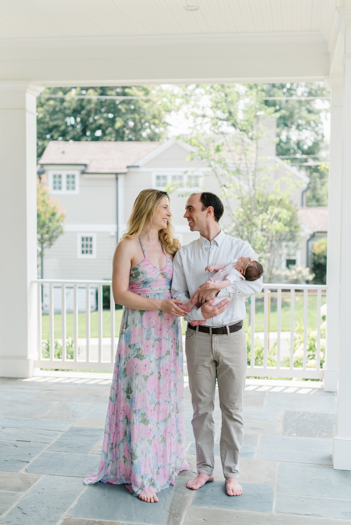 Couple holding their baby and smiling on a porch