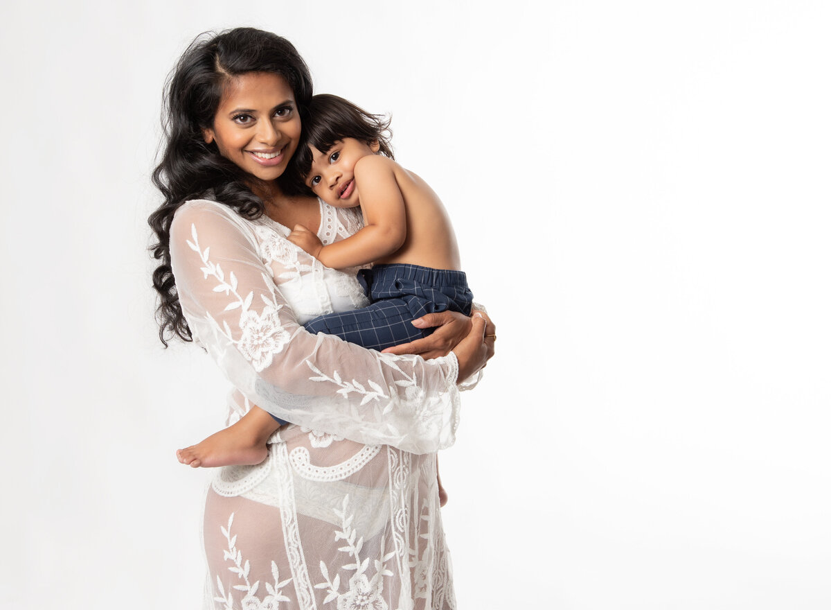 portrait of pregnant mom holding her son on white background