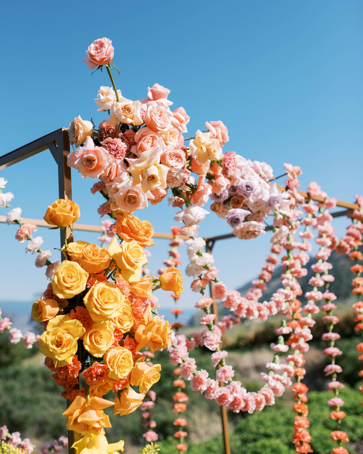 Bold floral installation of orange and pink roses by Valley Bloom Co, bright and airy wedding florals based in Kelowna, BC. Featured on the Brontë Bride Vendor Guide.
