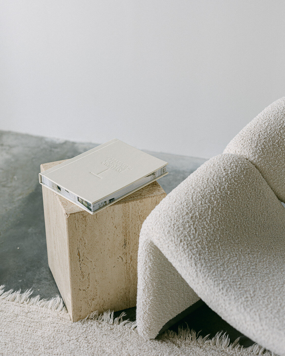 Un album photo haut de gamme et fait de cuir, déposé sur une table à côté d'un fauteuil.