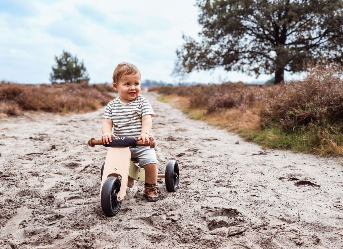 Kleine jongen rijdt op een kleine fiets en hij lacht in een bos - Foto door Pictures by Lisette