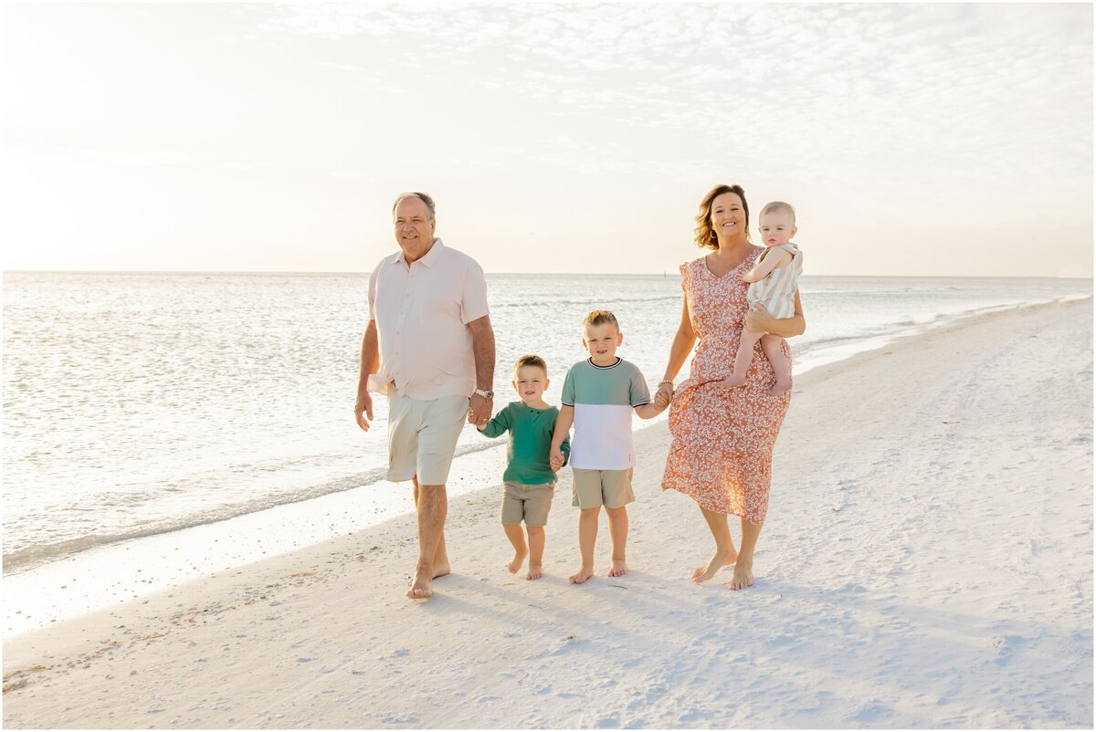 Natural light photo of family of five holding hands and walking down Siesta Key Beach
