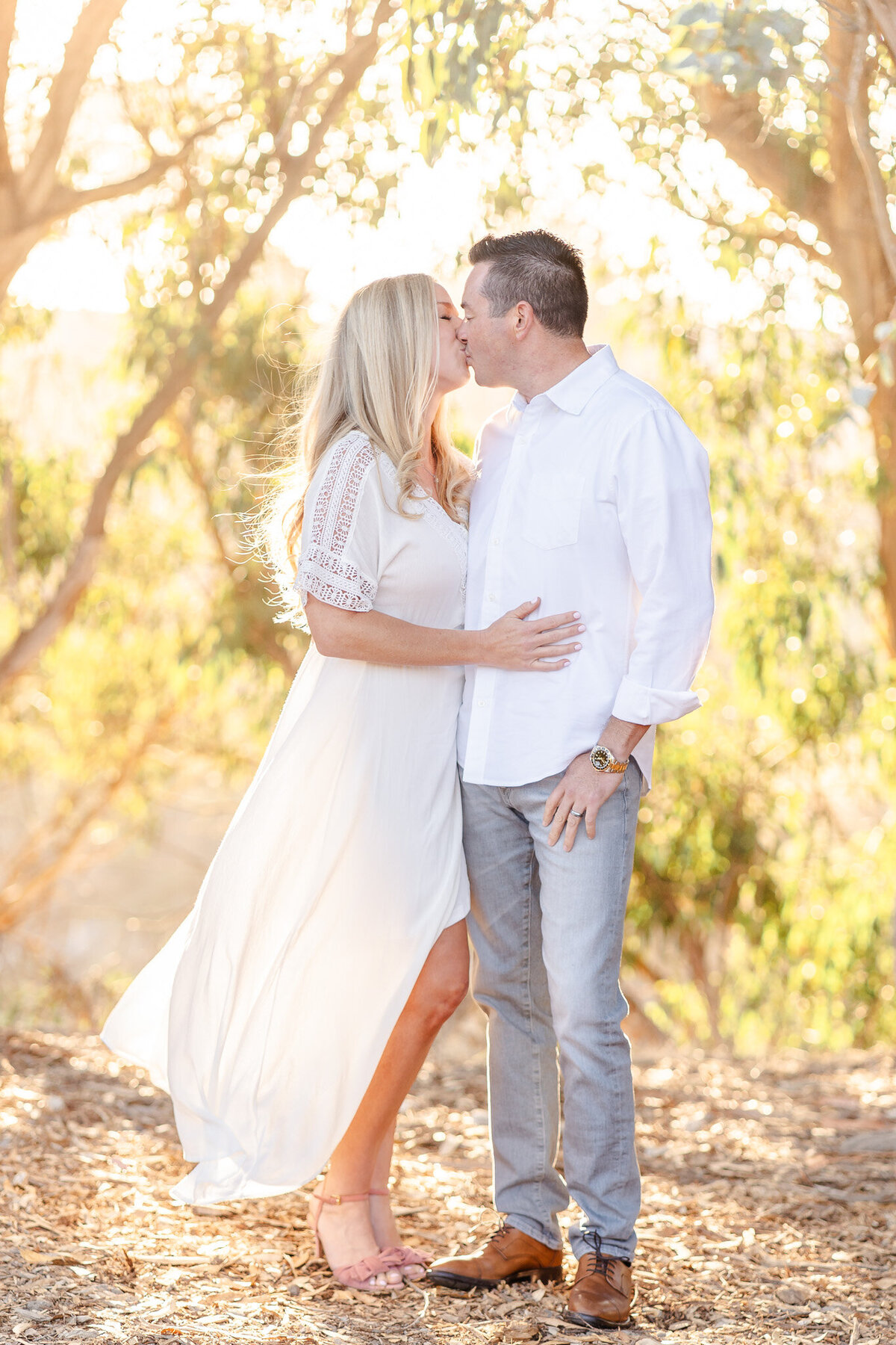bay area family photos of mom and dad kissing with glowing sunlight behind them