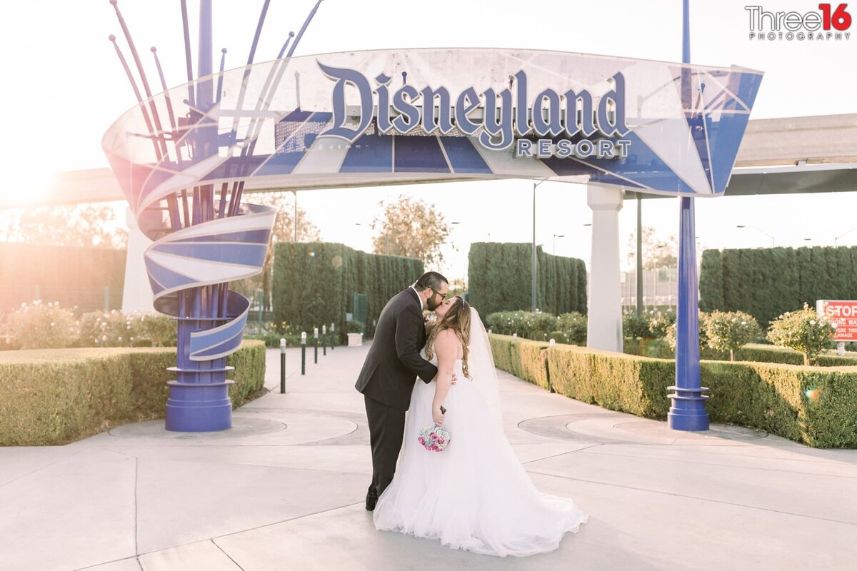 Bride and Groom share a kiss in front of the Disneyland entrance