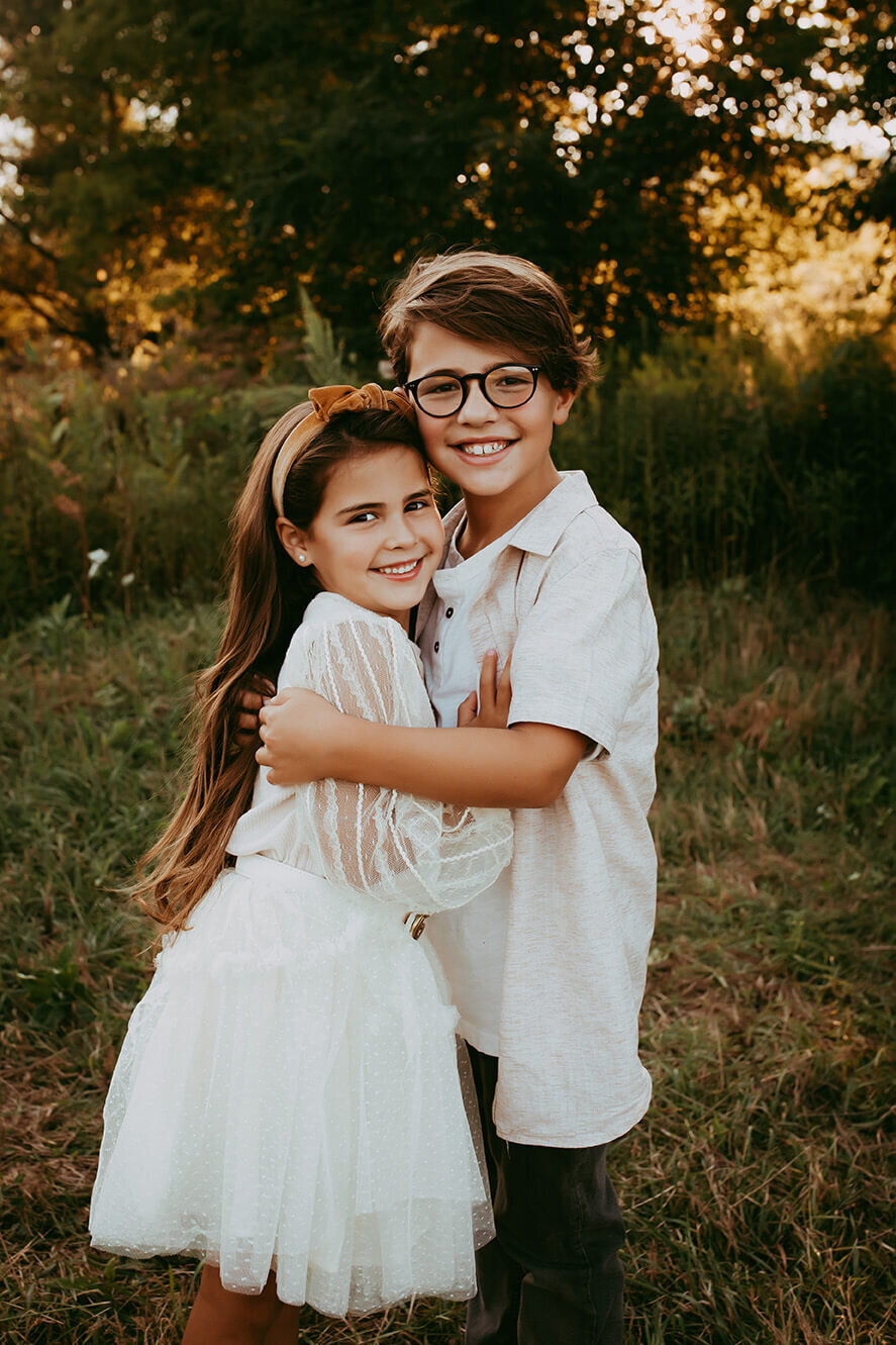 a brother and sister embraced with each other looking at the camera