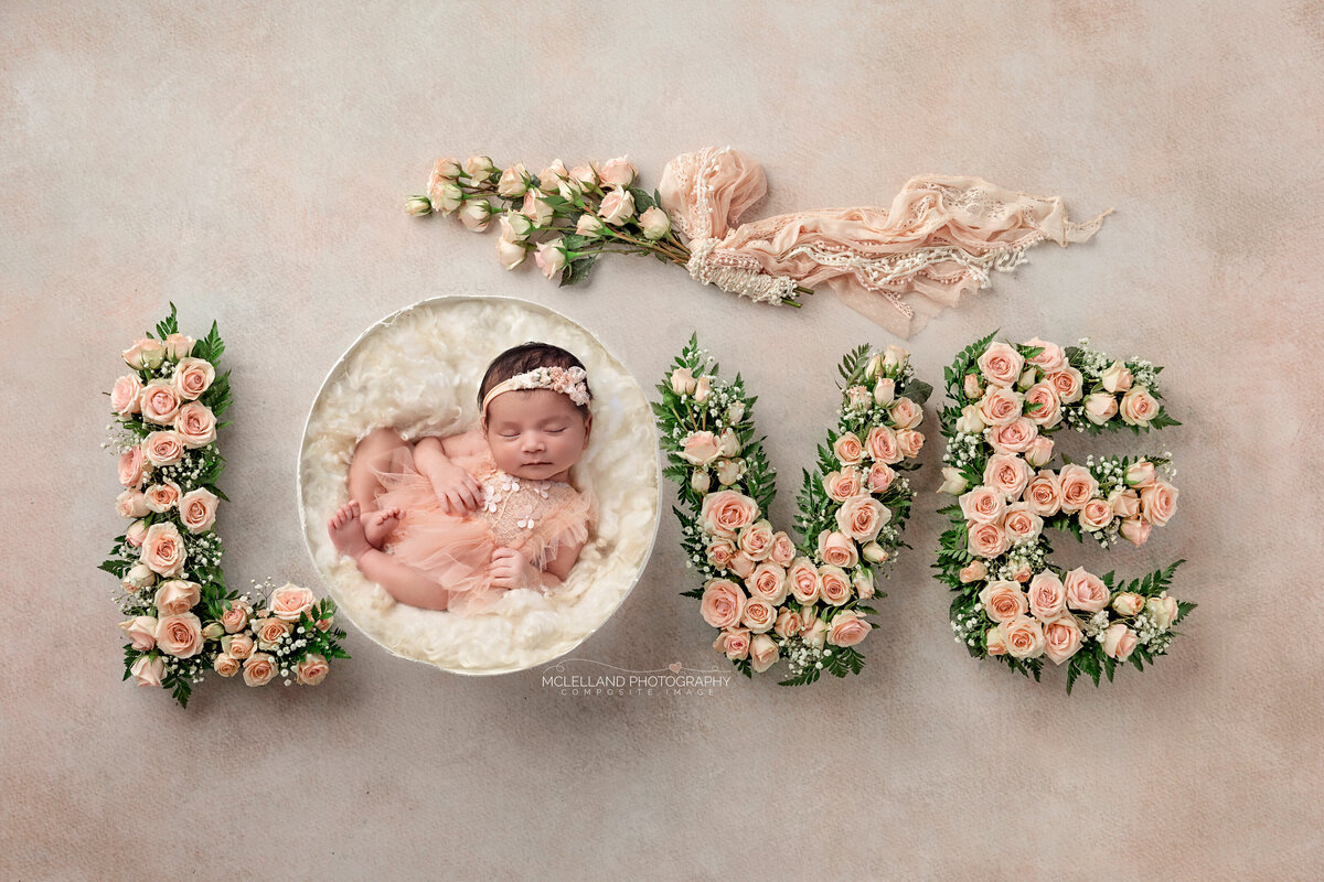 Newborn posed inside LOVE letters decorated with colorful florals