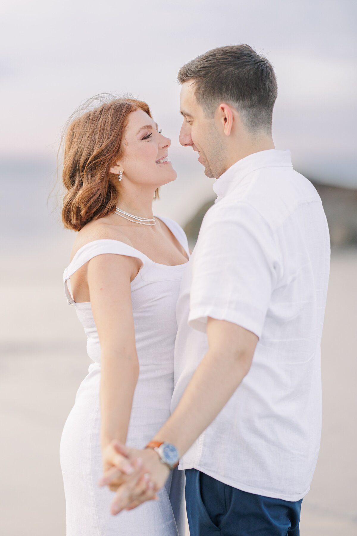 A close up of a couple holding hands and laughing during their Wingaersheek Beach photos.
