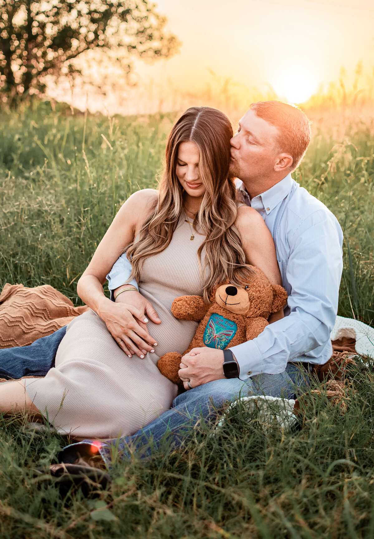 An expectant couple sits in a field at sunrise and bask in baby bliss at a League City Park.