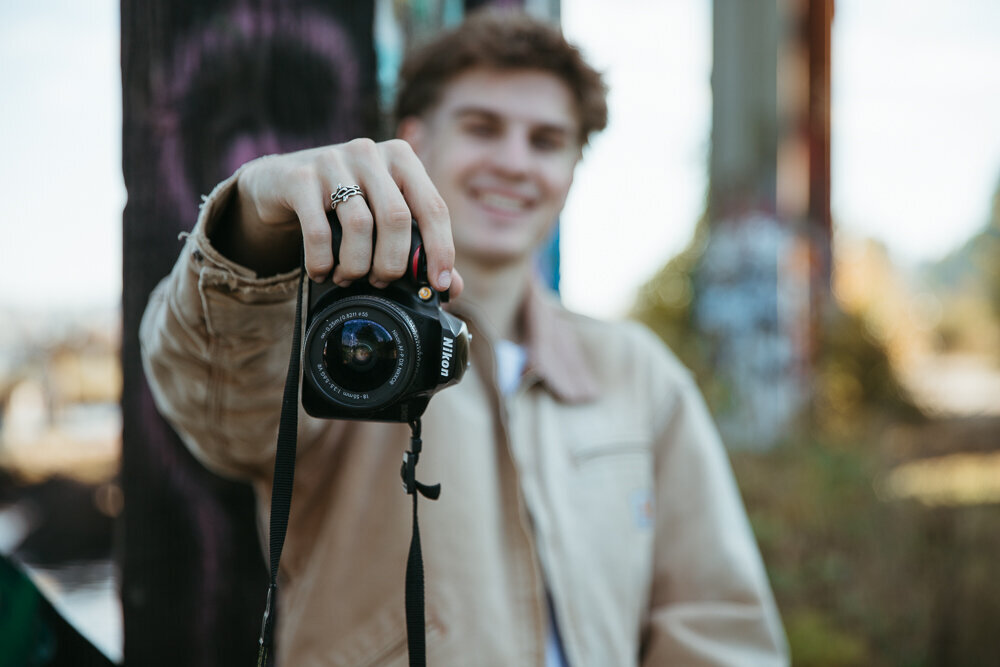 Graduating senior boy holding up his camera for a photo