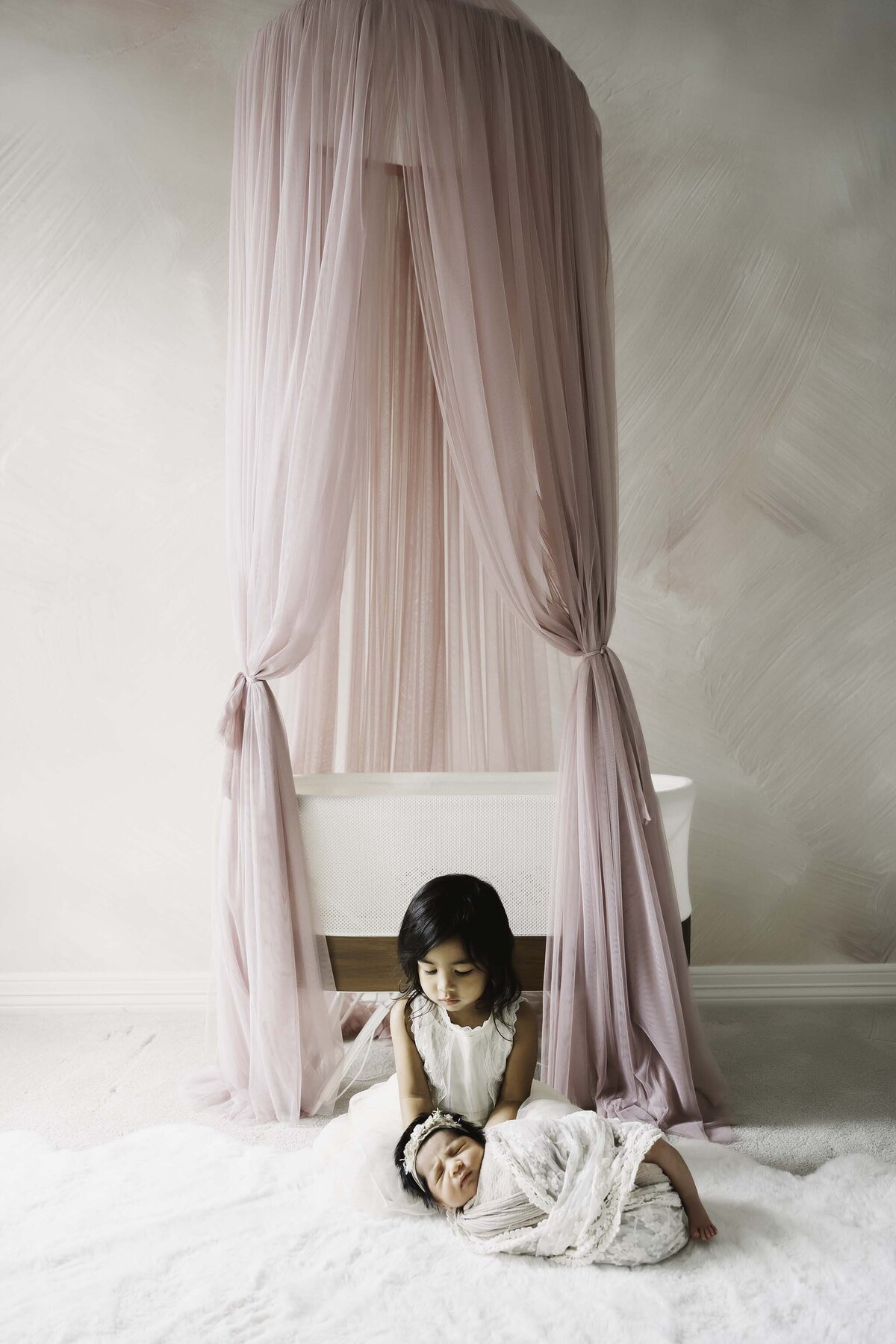 Big sister and baby sister in pink nursery