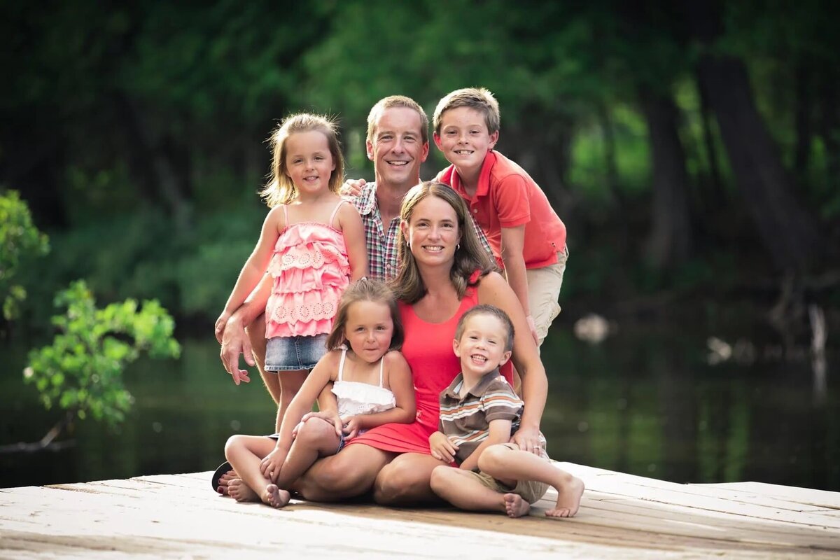 Two parents on a dock with their four small kids.