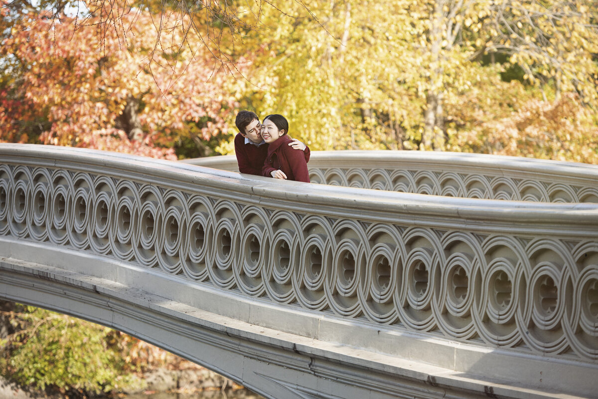 A couple laughing while standing on a bridge