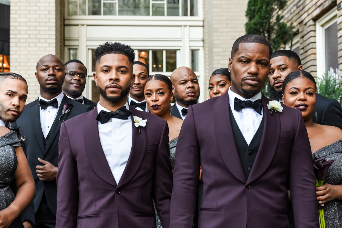 Stylish grooms with plum tuxedos and bridal party