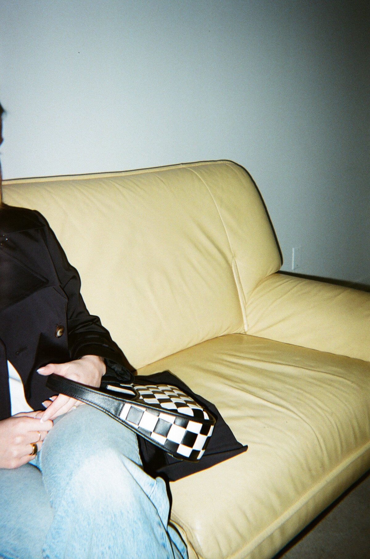 woman sitting on chair holding a checkered handbag