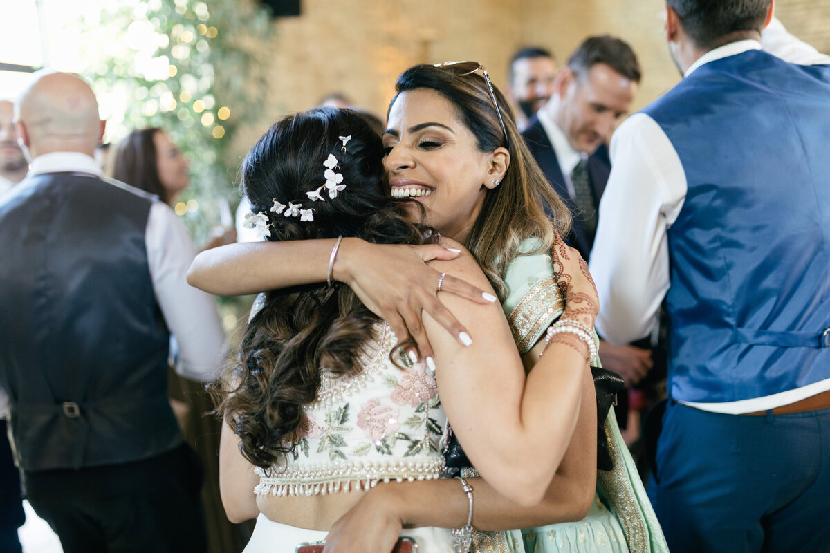 wedding guest hugs bride during indian wedding ceremony
