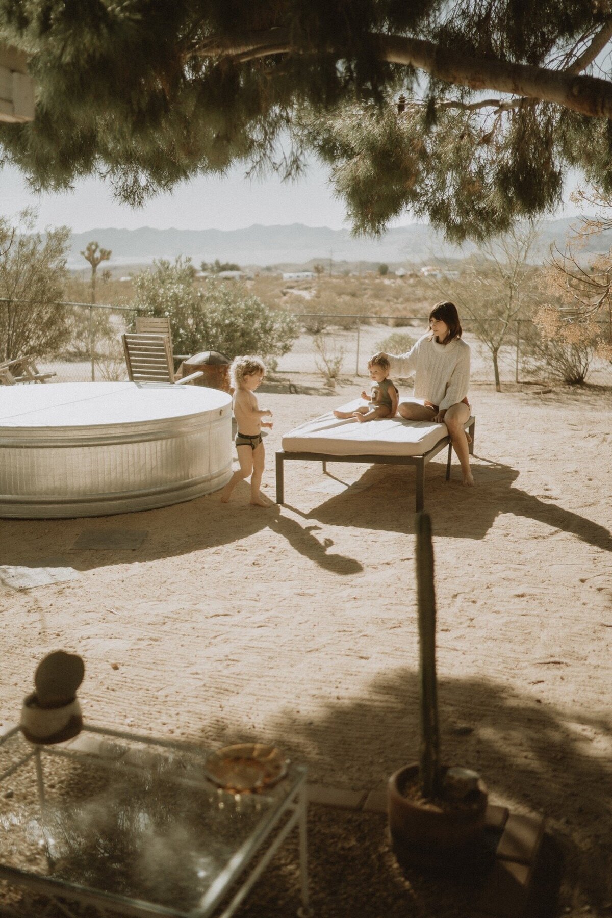 mother sitting on outdoor seating with two children at joshua tree california ranch