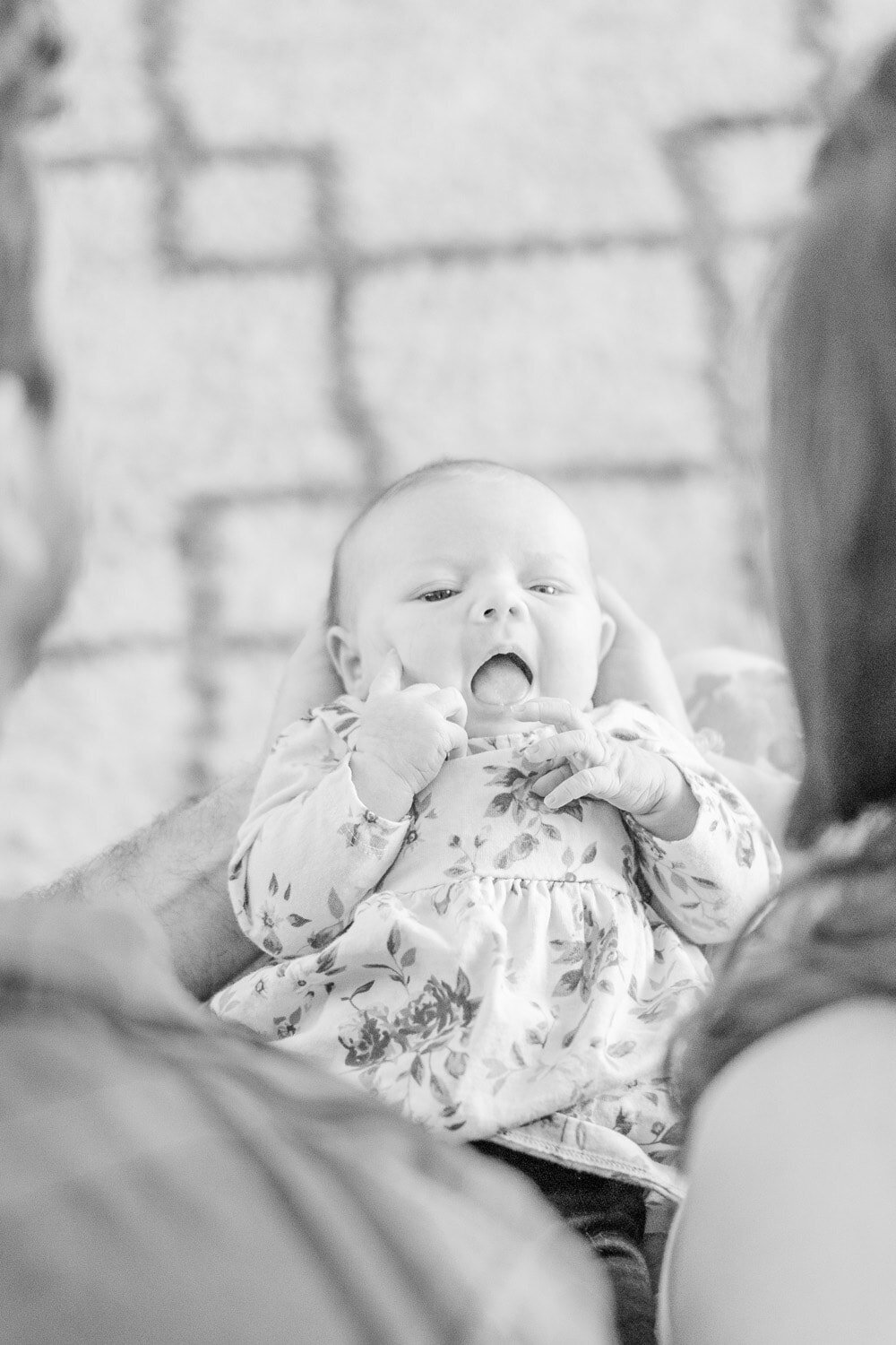 baby girl held by parents during a lifestyle newborn photography in Alexandria, Virginia