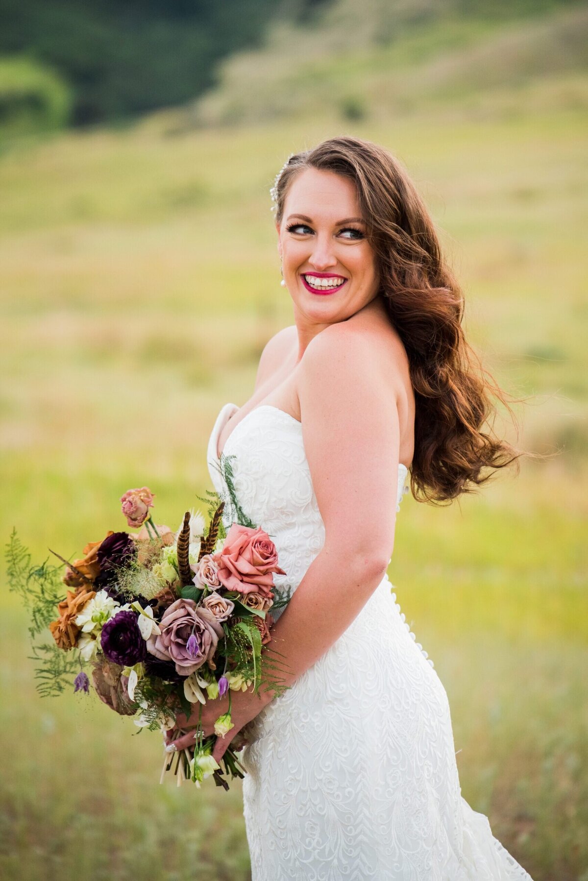 A bride glances over her shoulder, smiling at her groom off camera at The Manor House venue in Denver, Colorado.