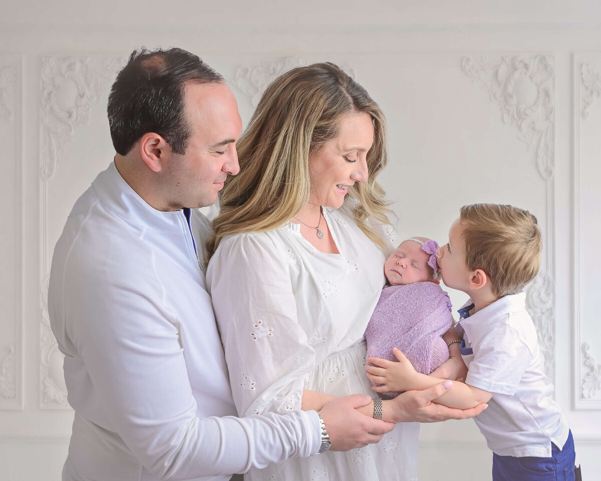 Family photo of parents and sibling in an in-home newborn photo session with Beth Benecki .