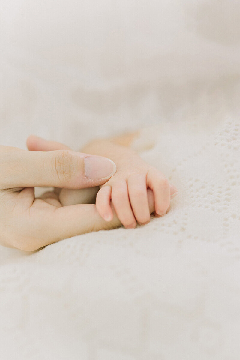ママの指を握っている新生児の赤ちゃんの手が愛おしいナチュラル・ニューボーンフォト
