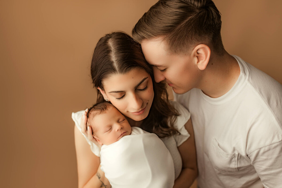 infant being held and snuggled by mom and dad