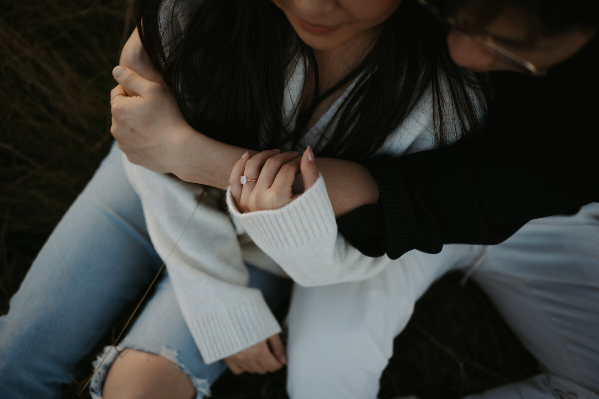 Photo of engaged couple snuggling and close up of engagement ring