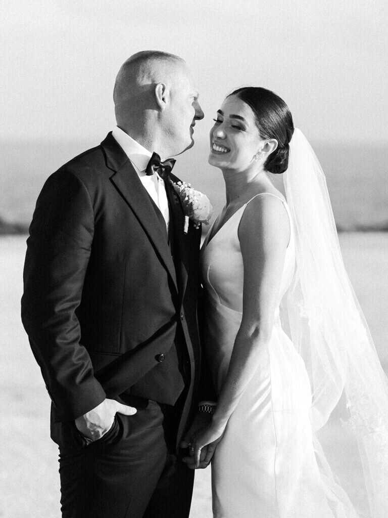 A joyful black-and-white portrait of the newlyweds sharing a sweet moment of laughter, capturing their love and happiness on their wedding day. Captured by Claudia Amalia Photography.