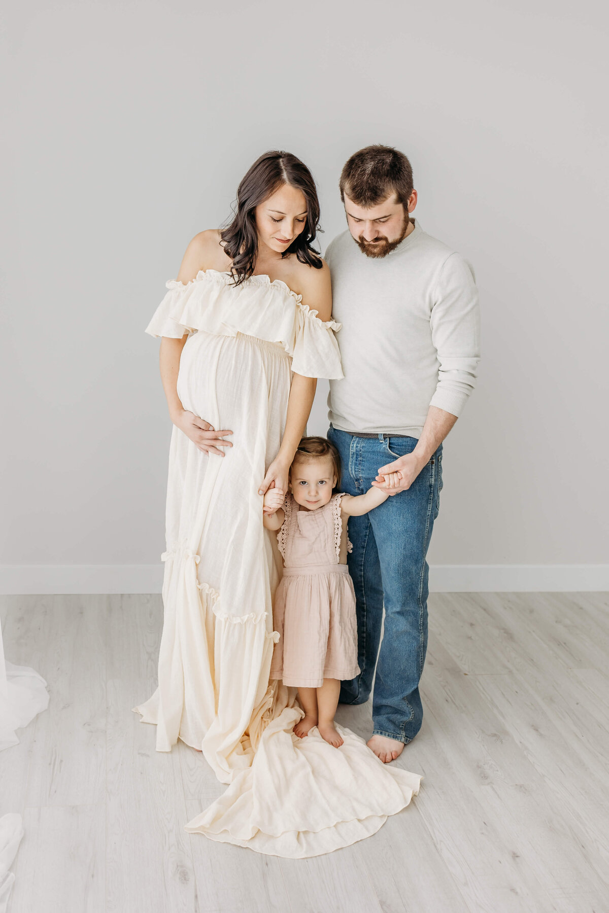 Yound family with little girl expecting another baby in white dress