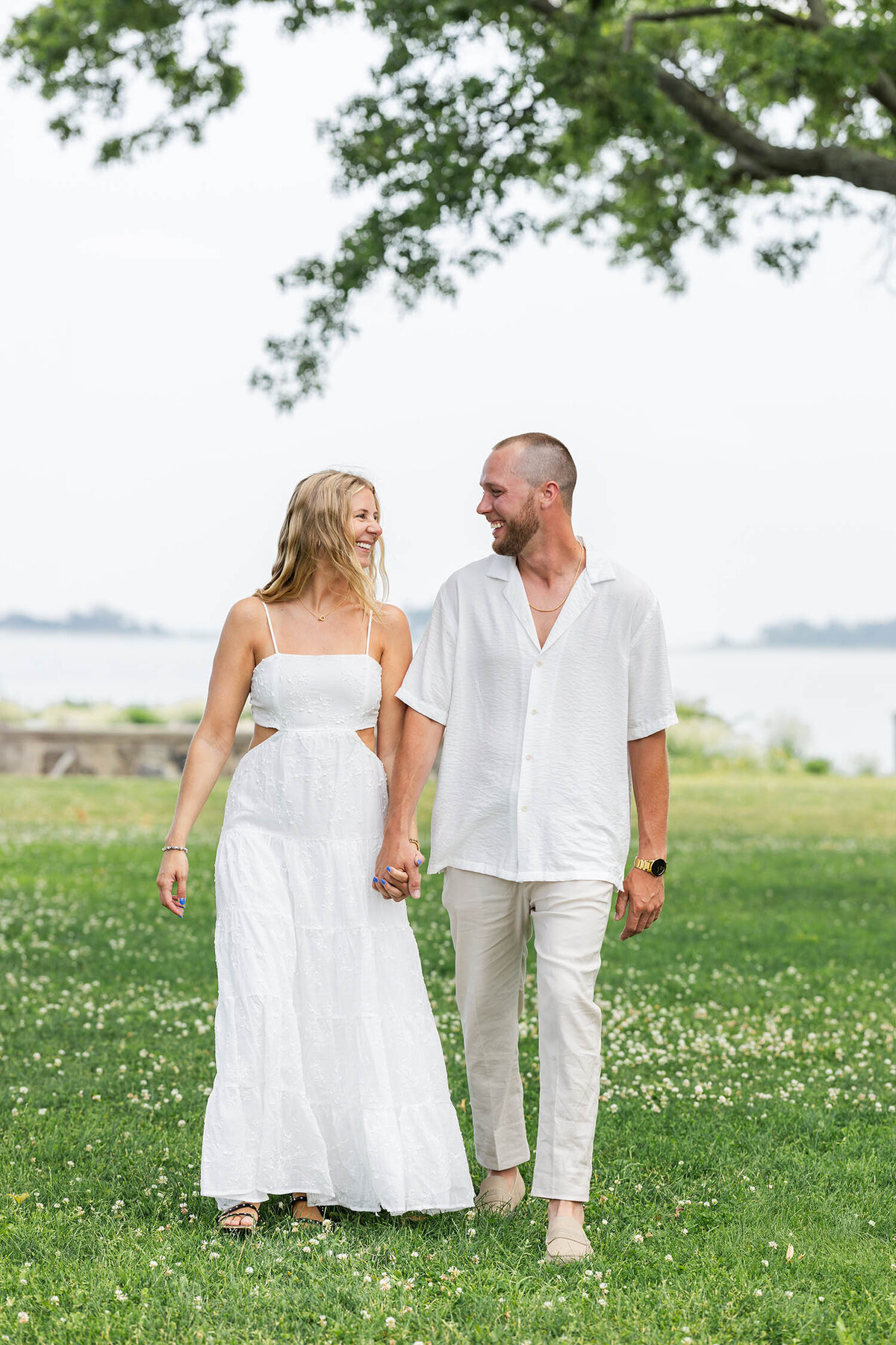 Couple holding hands in a clover field during a romantic Coastal Connecticut photo session