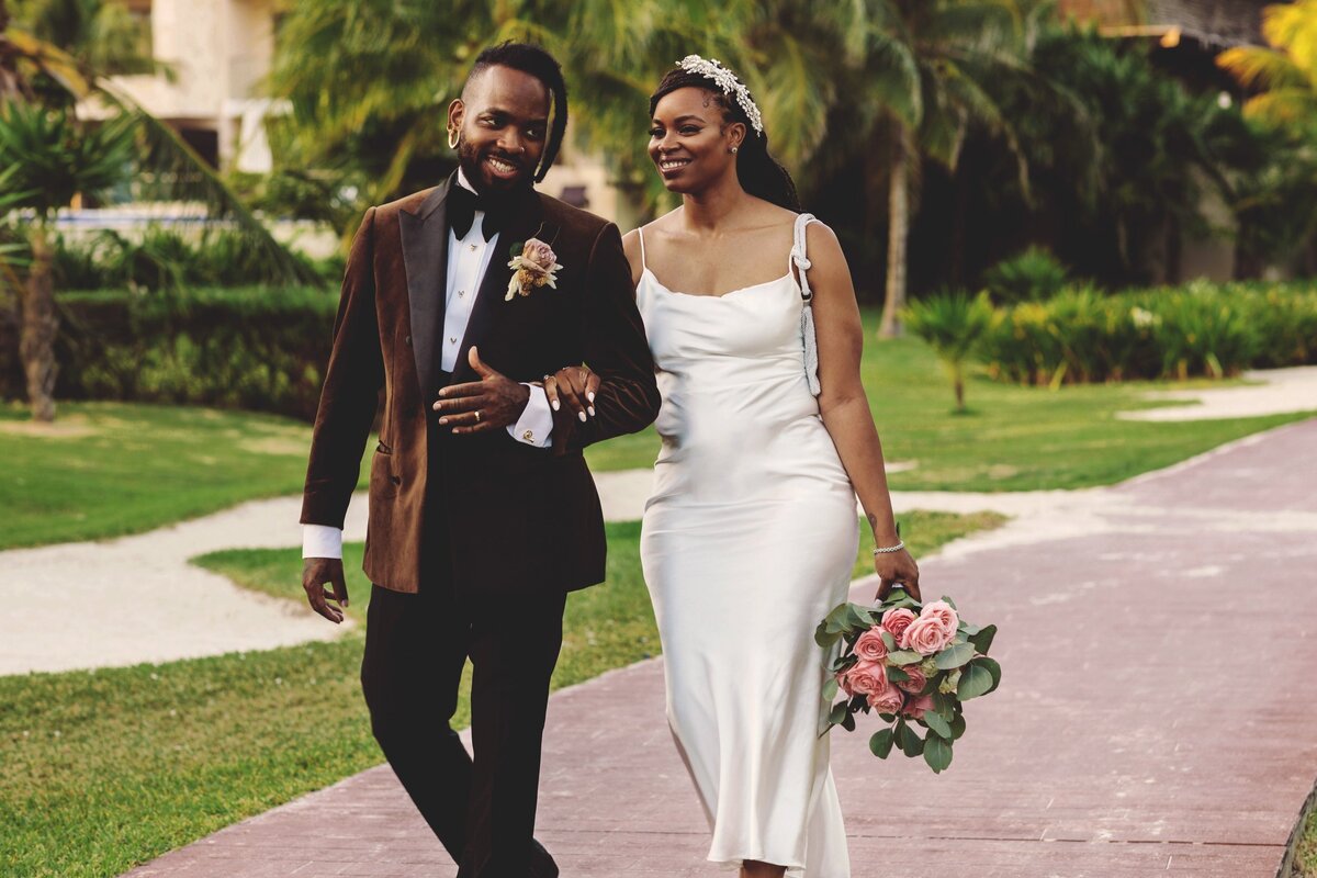 Bride and groom laughing as they walk down path at Cancun wedding