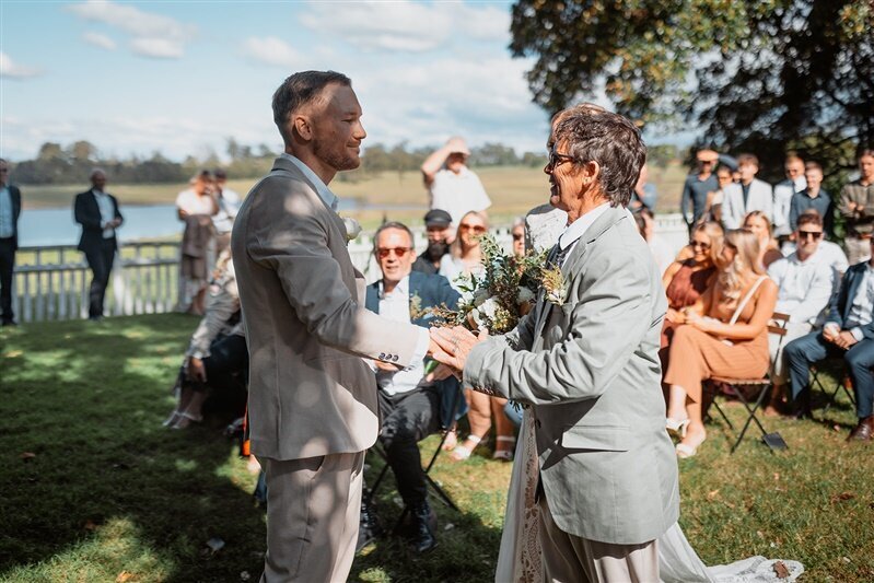 Experience the heartwarming moment when the Groom and Bride's Dad share a meaningful handshake, symbolizing the beautiful transition of care and trust.
