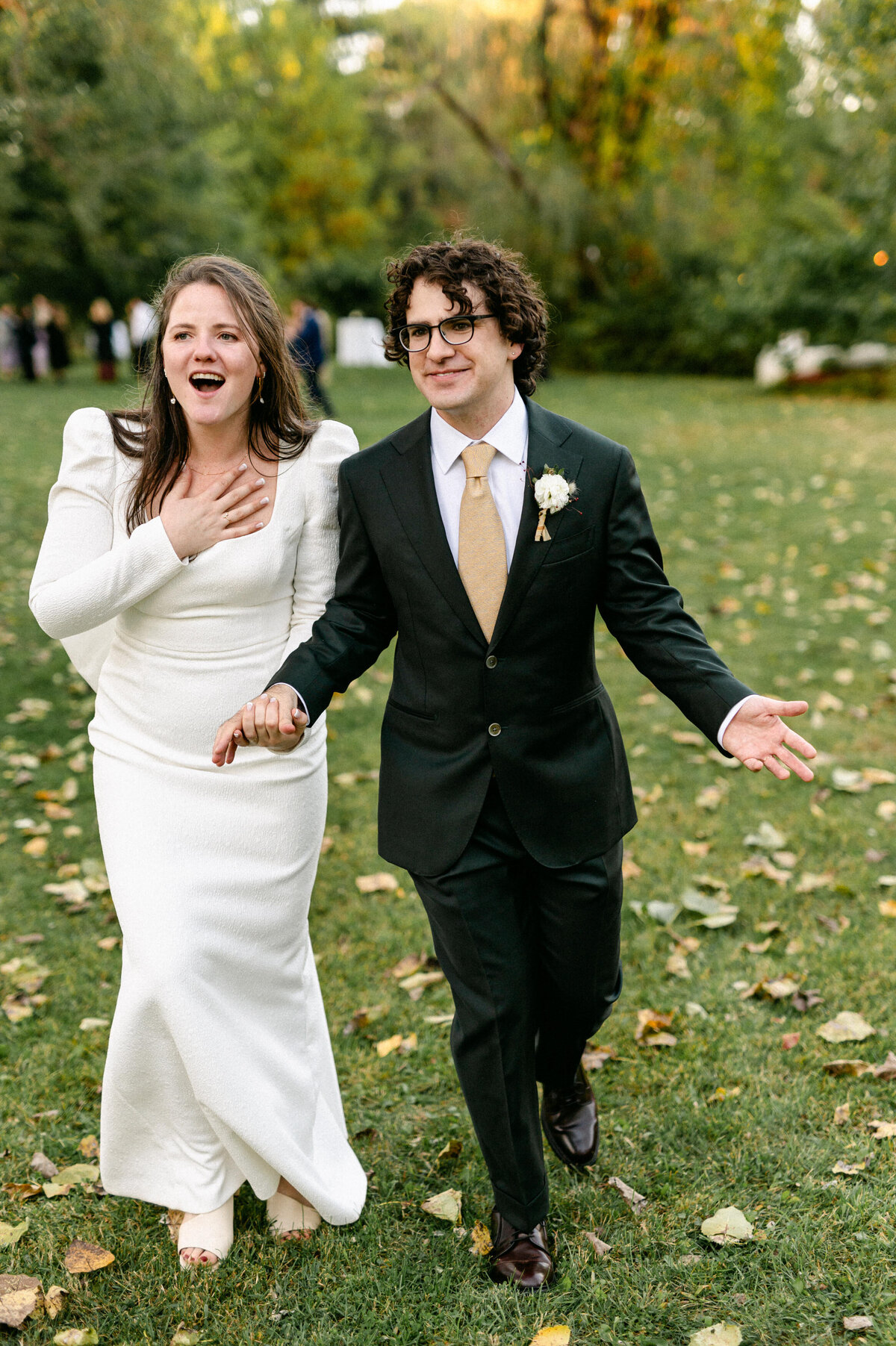 Bride gasping with hand on chest hand in hand with groom