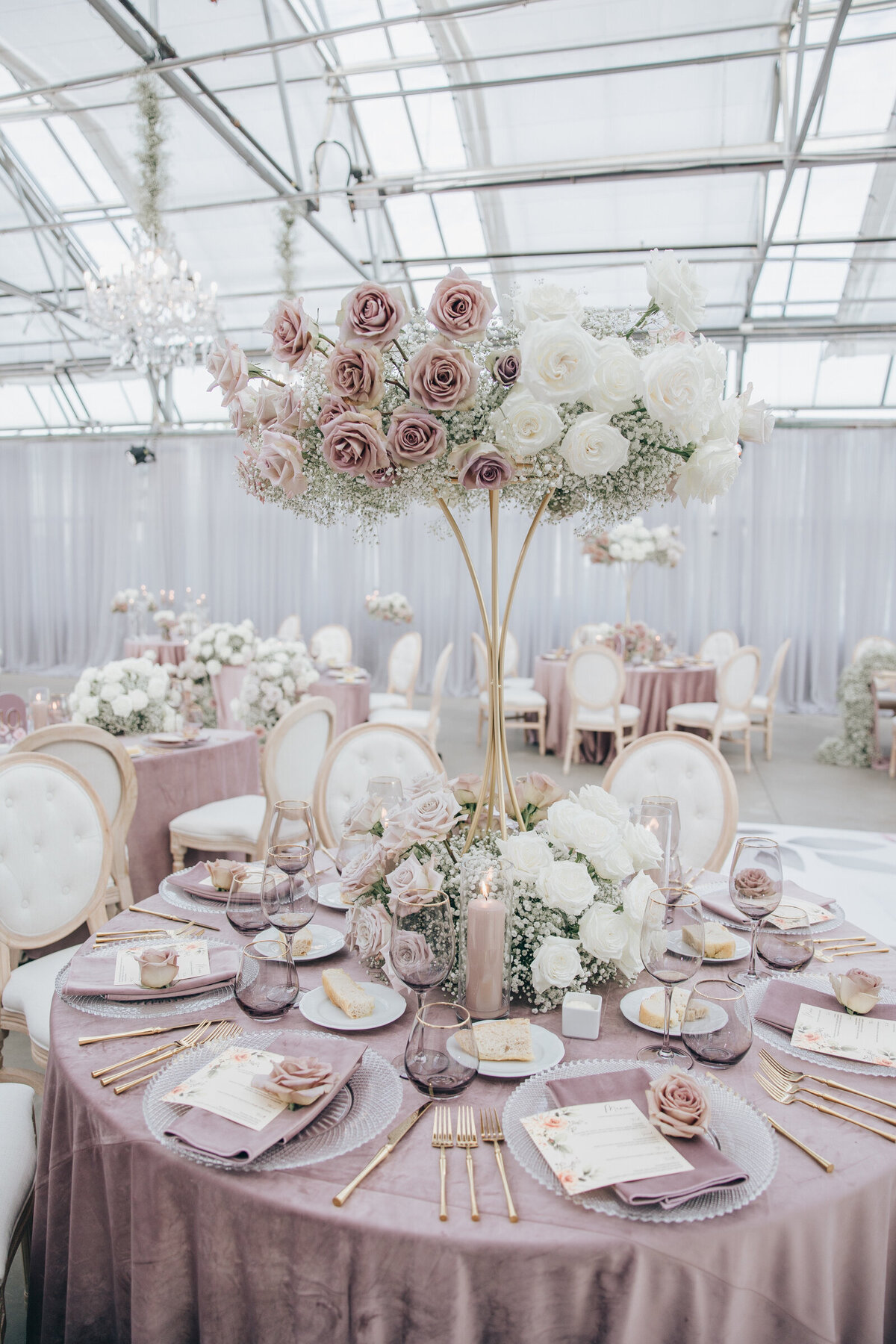Luxurious dinner decor with gold cutlery, crystal plates, and lavender table cloths