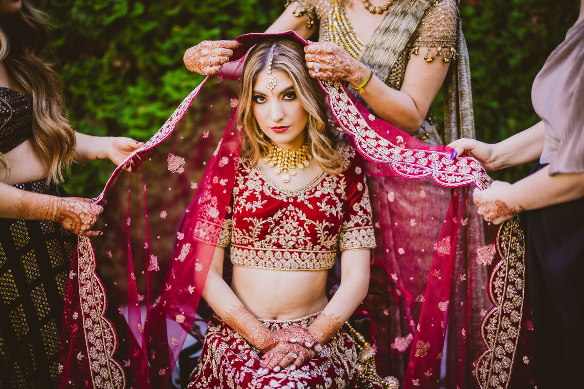 Indian fusion white bride getting ready before the hindu ceremony with the dupatta veil setting