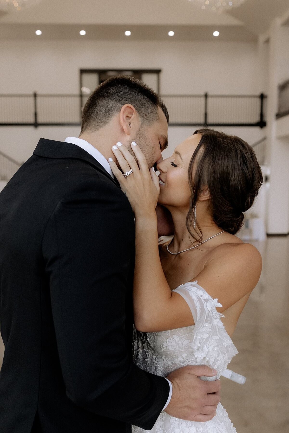 groom dressed in black tux bride in elegant white dress kissing