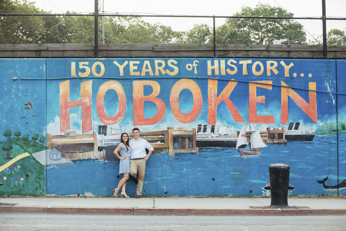 Couple by history mural during summer engagement photo in Hoboken New Jersey