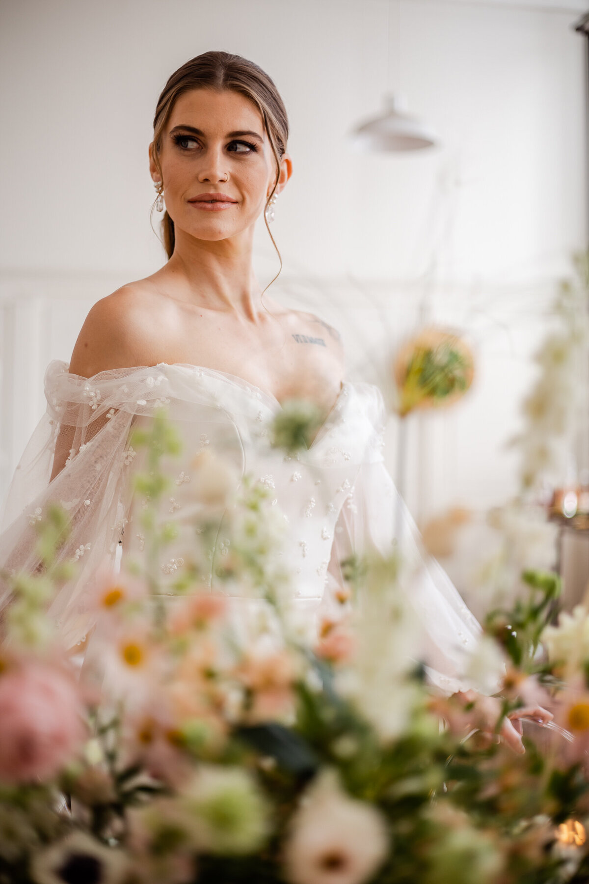 A bride looks over her shoulder on her wedding day behind flowers.