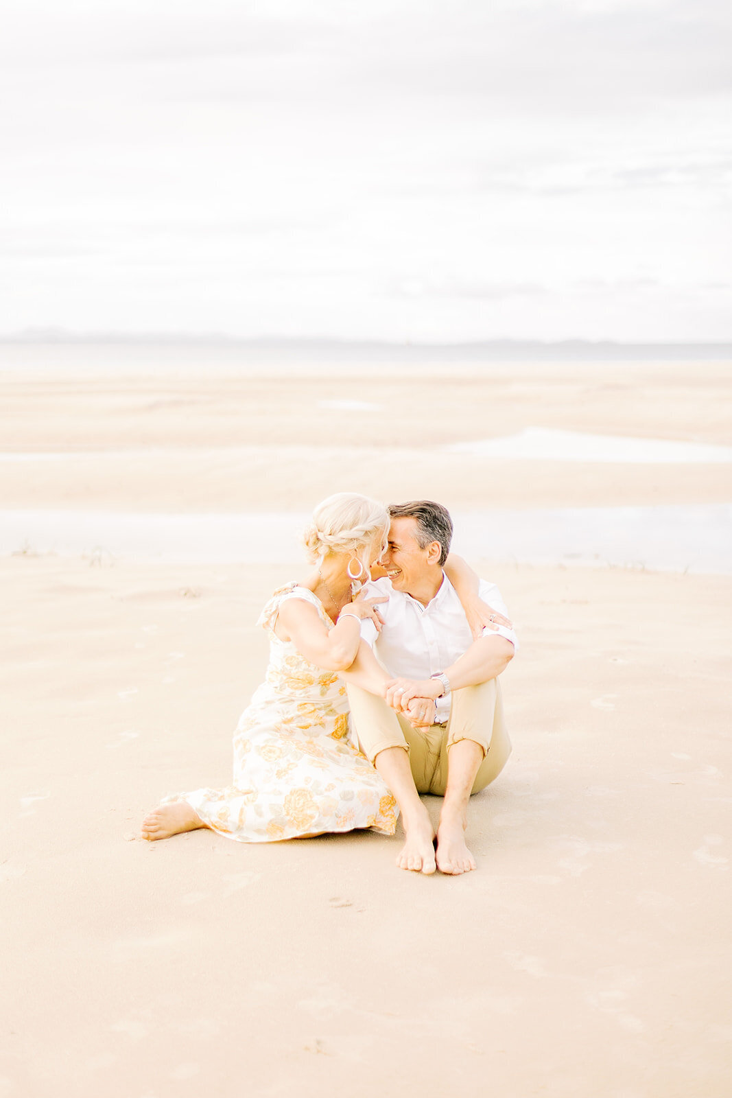 wife holding husbands arm on the beach