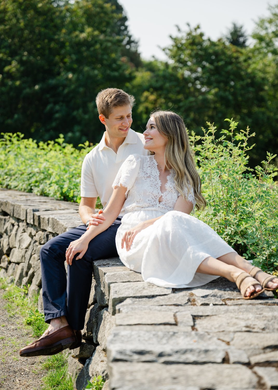 bride and groom pose on rock wall in seattle 