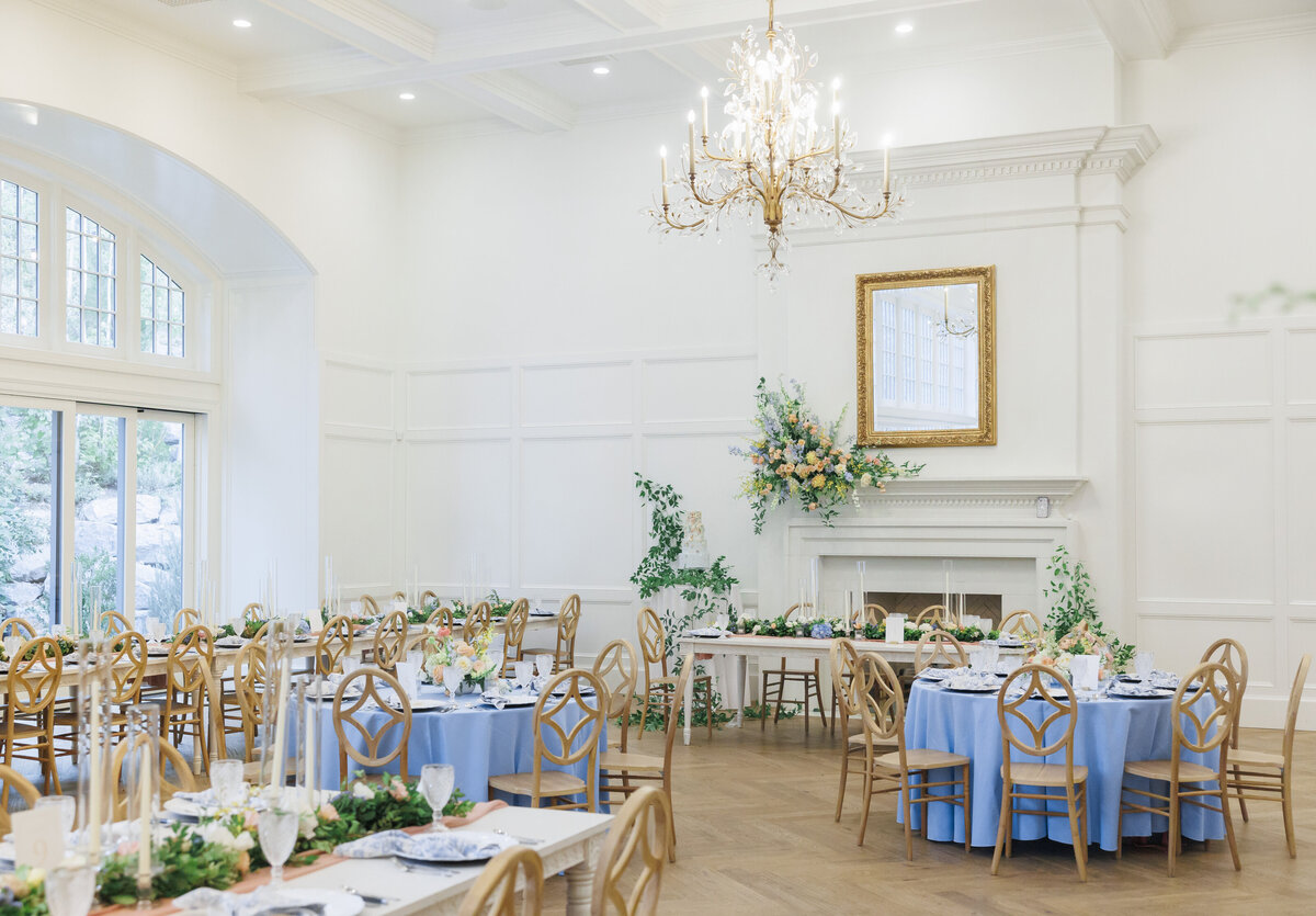Detail of a wedding reception at Twenty And Creek, with soft blue linens, white candlesticks, and pastel flowers