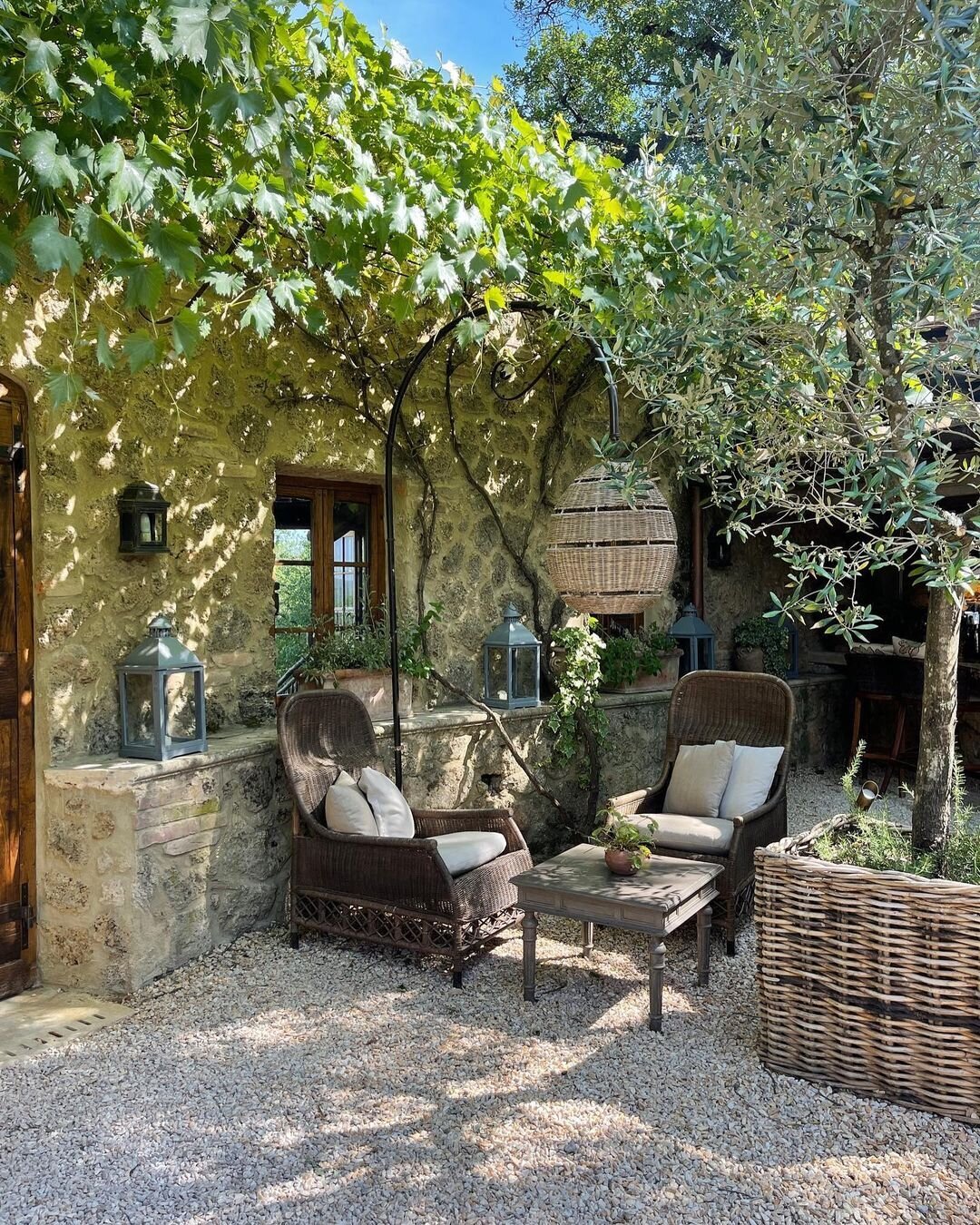 A cozy Tuscan courtyard with wicker lounge seating and a leafy canopy for shade