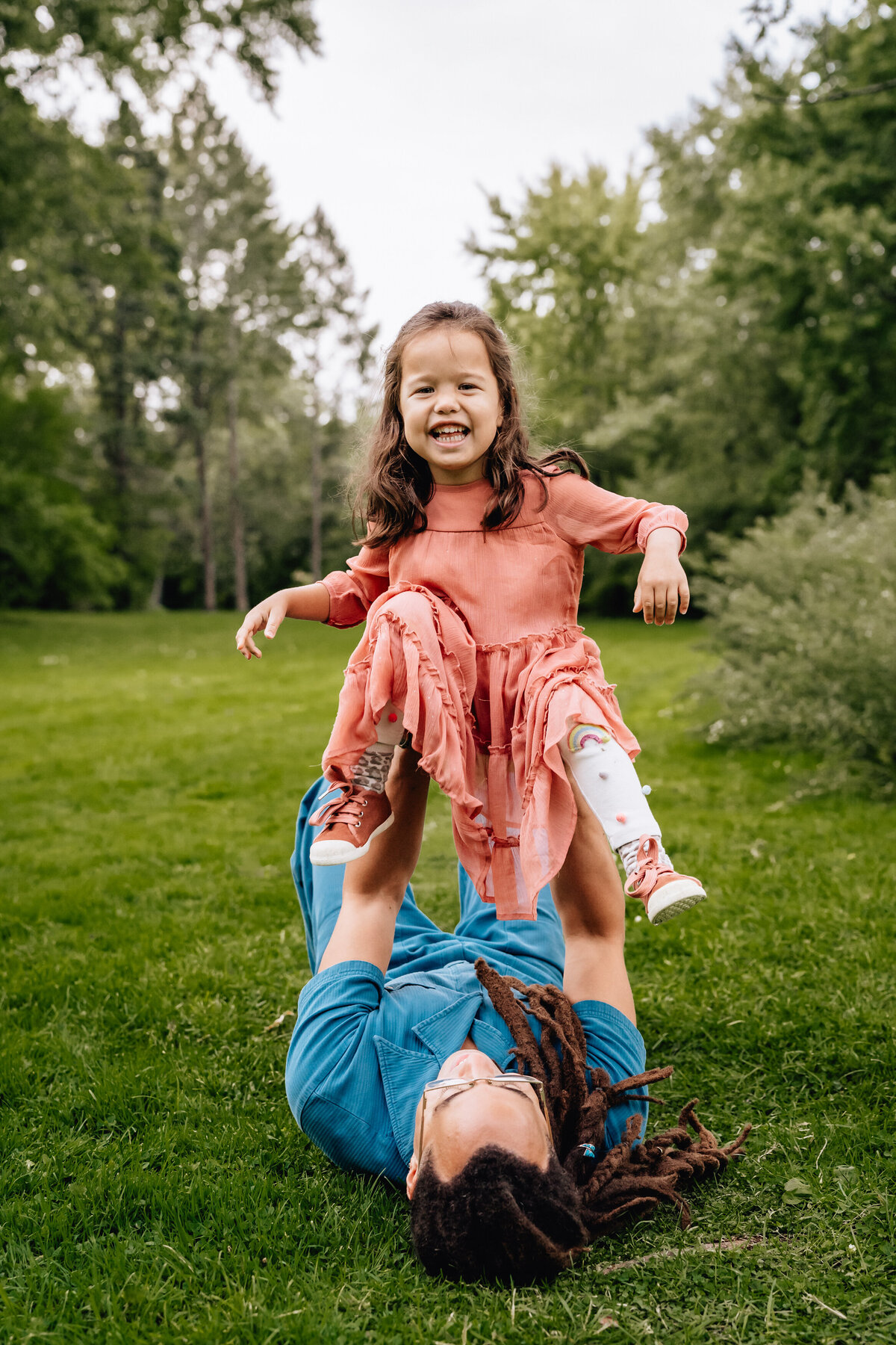 A child laughs while her dad holds her up.