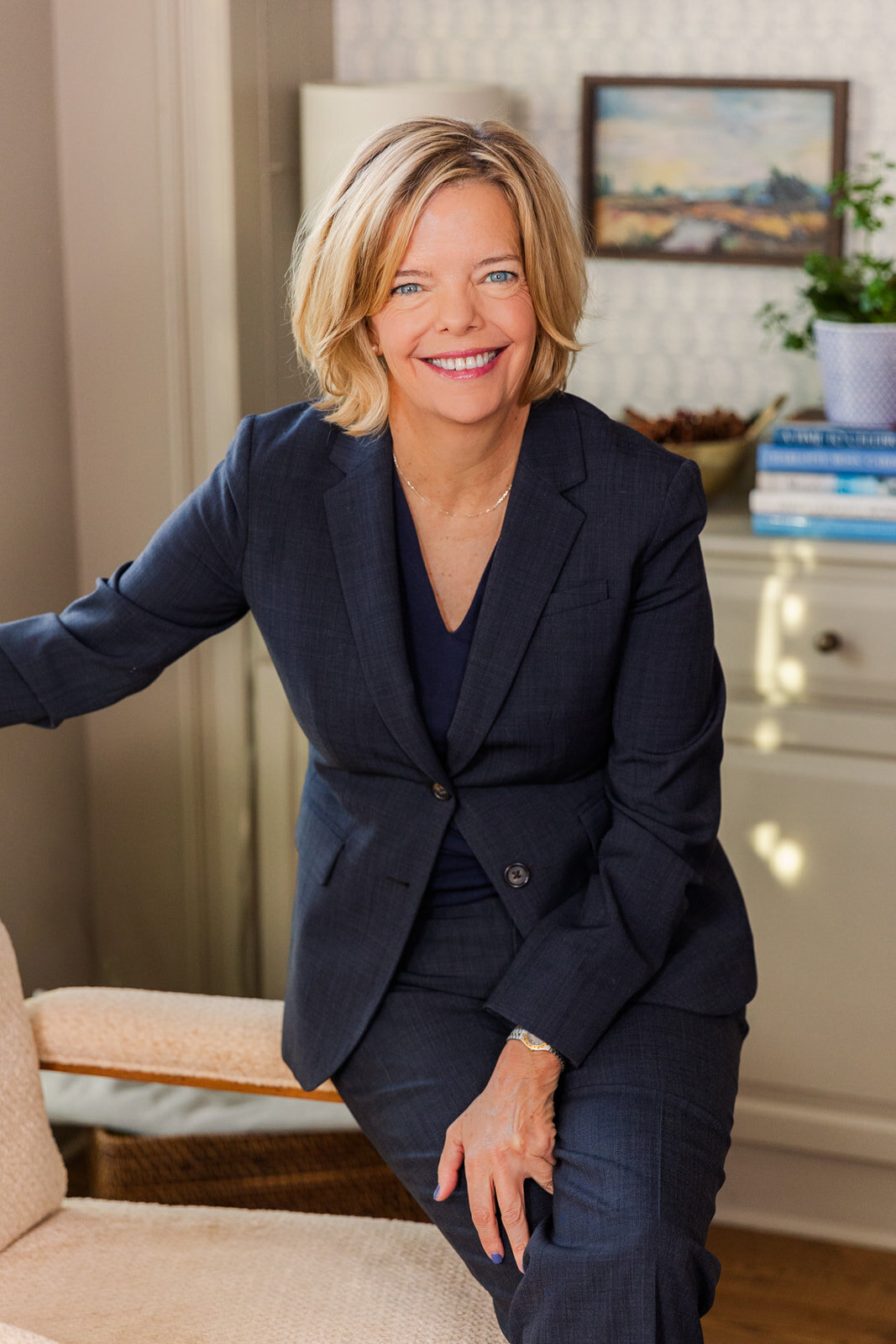 woman wearing a denim suit siting legs crossed on the edge of a chair at home during portraits session