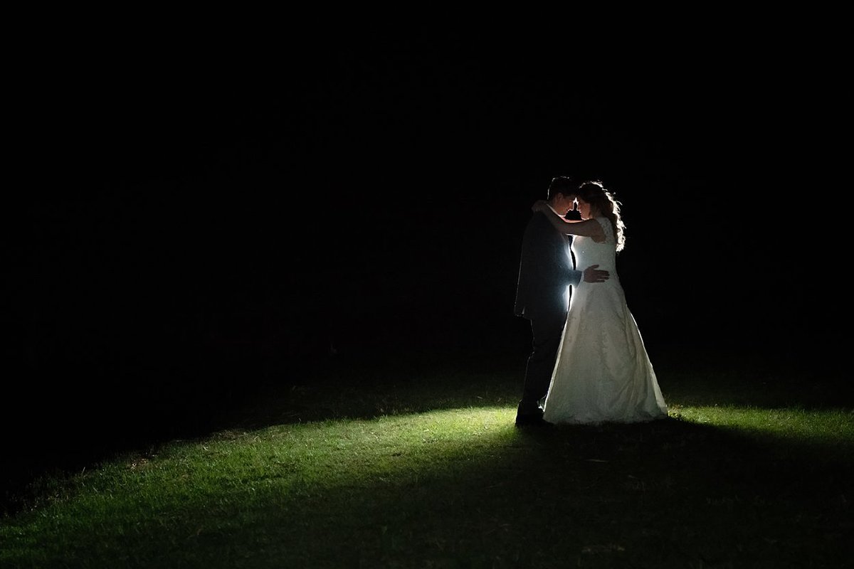 Artistic night portrait of Bride and Groom outdoors lit from behind with flash