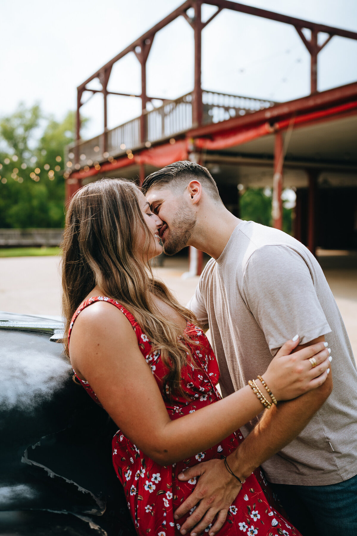 newly engaged couple kissing by vintage car