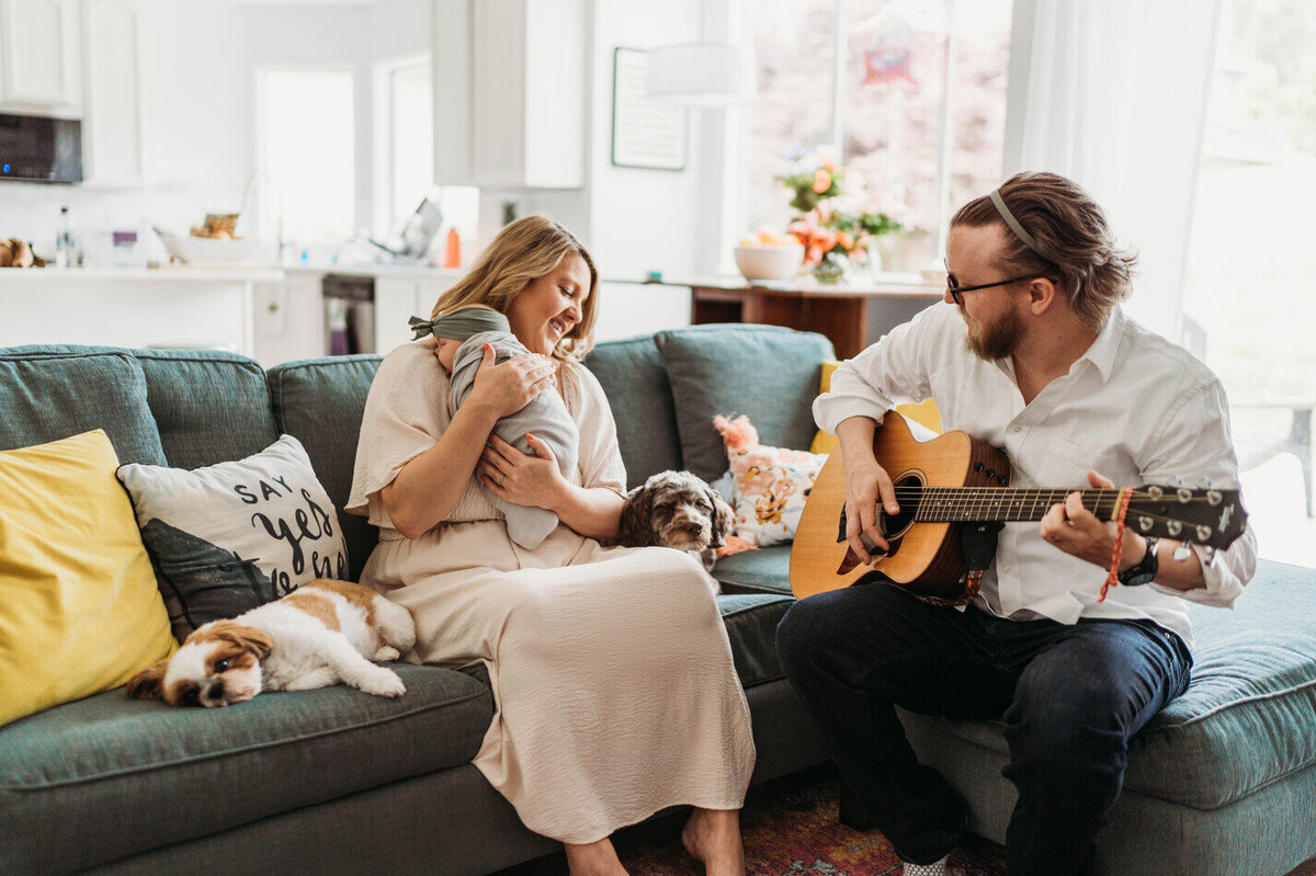 mom-holding-baby-while-dad-playing-guiltar-in-their-seattle-home