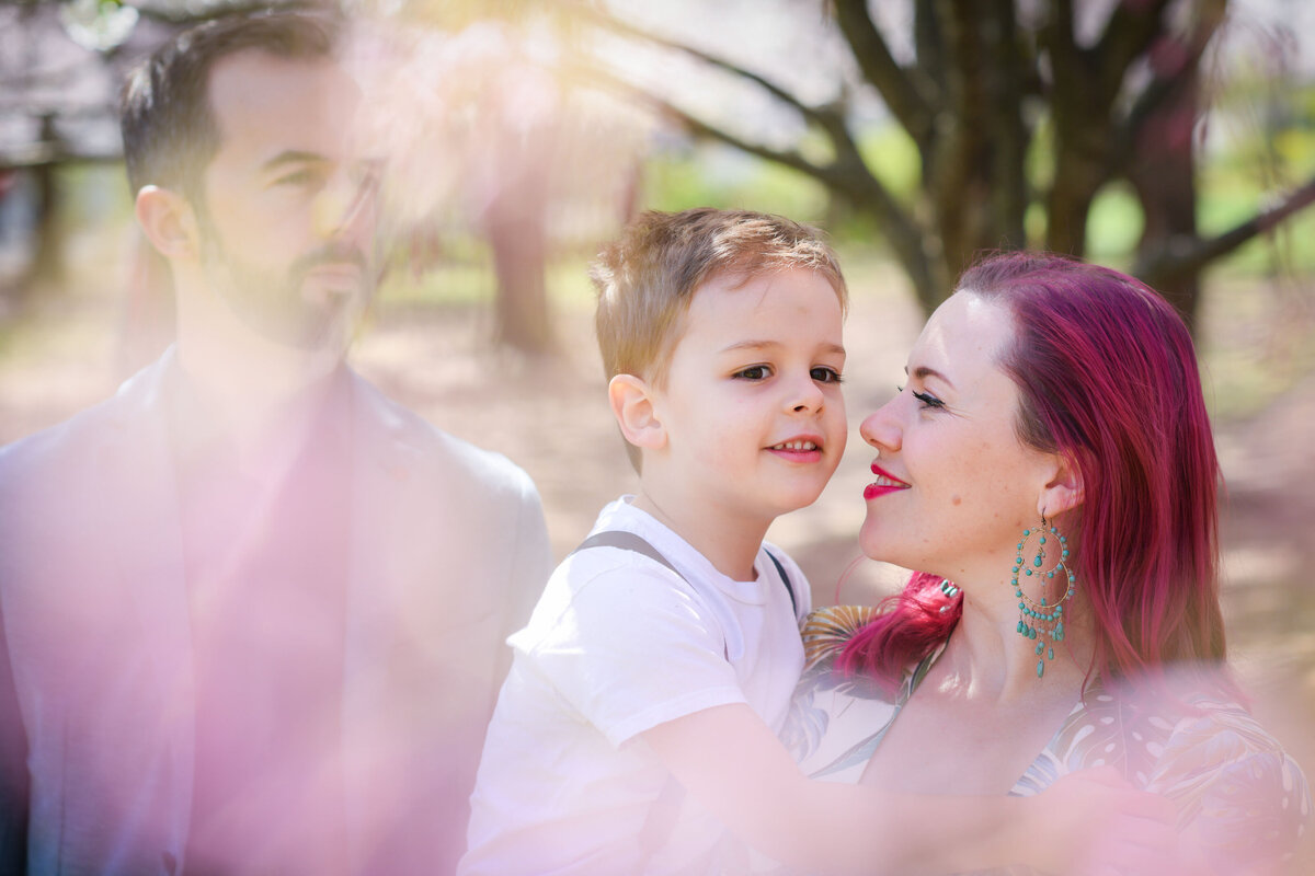 A person holding their child with their partner standing next to them
