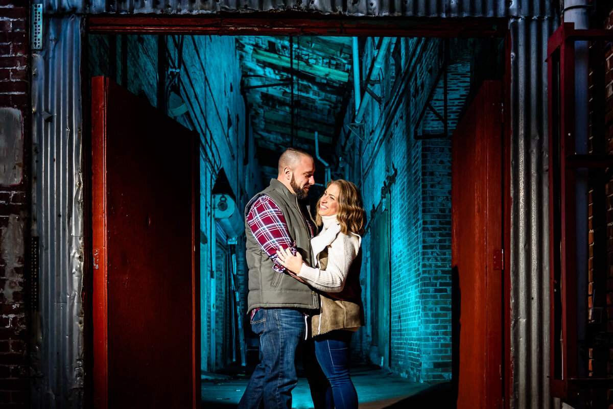 A couple embraces in front of an industrial building backdrop